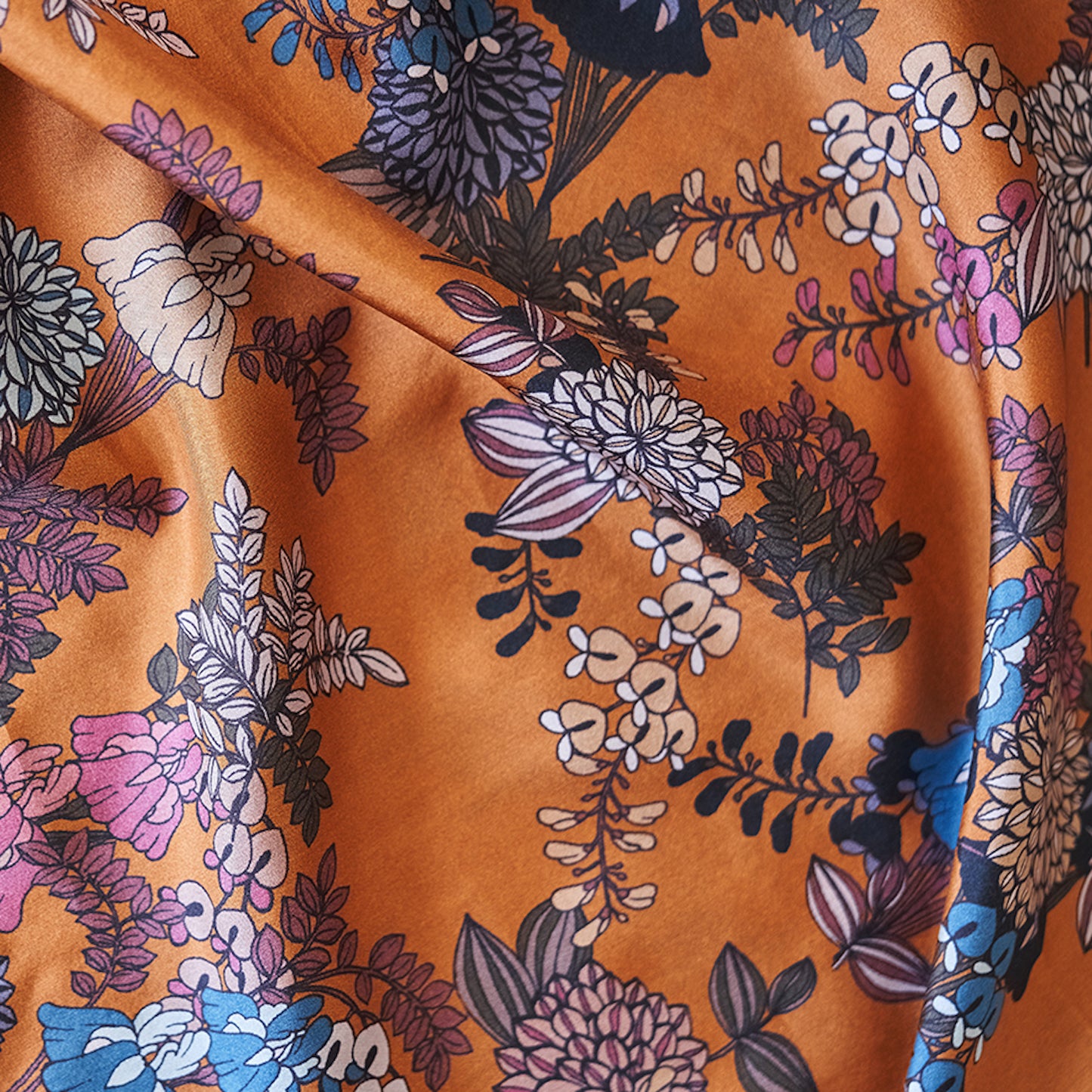 Foulard en soie 77 Meilleur Ami Paris. Gros plan sur les fleurs colorées, sur fond caramel lumineux.