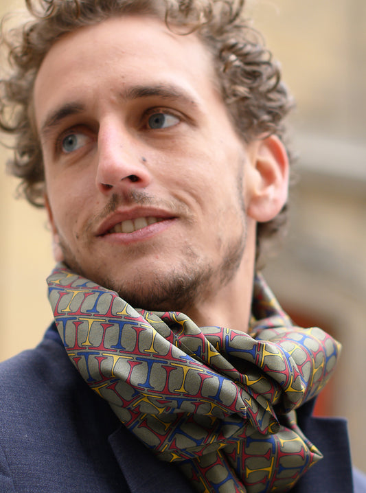 Foulard en soie 05, porté homme, Meilleur Ami Paris. Inspiré des motifs cravate des années 60/70 aux couleurs d'automne, kaki, rouge, bleu et jaune.