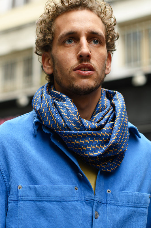 Foulard en soie 111 Meilleur Ami Paris, porté homme, motifs bleu et ocre sur veste bleue.