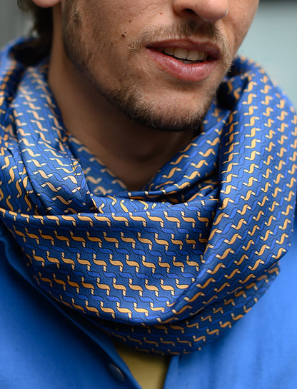 Foulard en soie 111 Meilleur Ami Paris, porté homme, zoom sur les motifs bleu et ocre. 