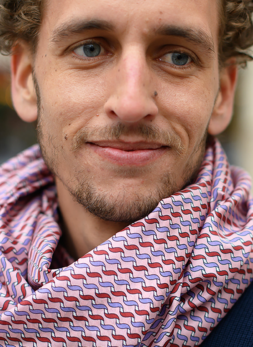 Foulard en soie 113 Meilleur Ami Paris, porté homme. Motifs bordeaux, violets et blancs sur fond rose pâle..