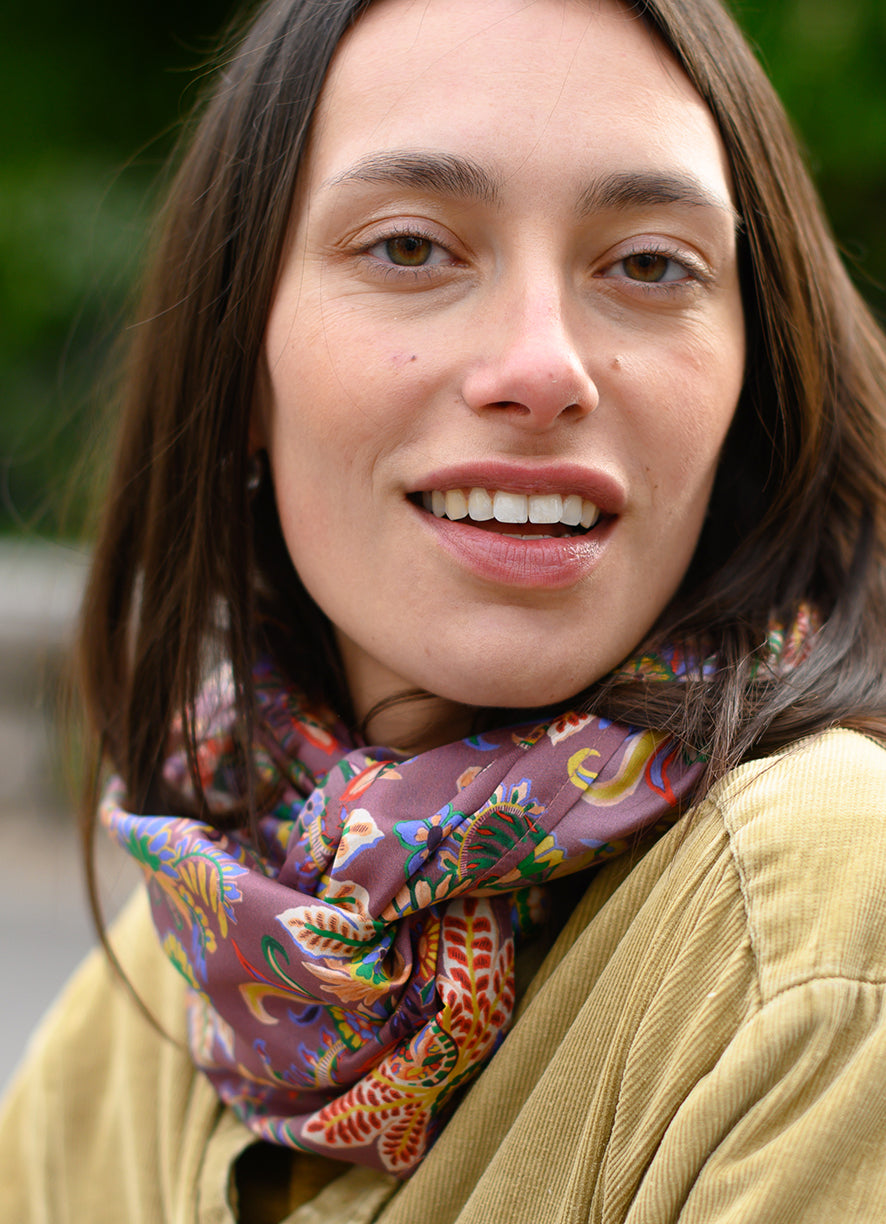 Foulard en soie 115 Meilleur Ami. Fleurs et cashmeres sur un fond violet bordeaux, porté femme, vue de face.