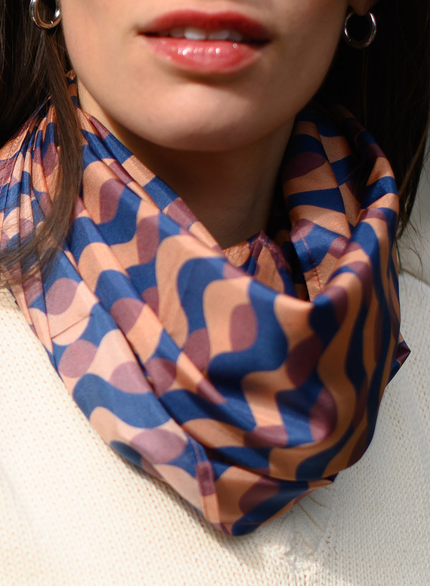 Foulard en soie 118 Meilleur Ami Paris, porté femme. Jeu graphique aux tons chauds, bordeaux, bleu nuit et vieux rose.