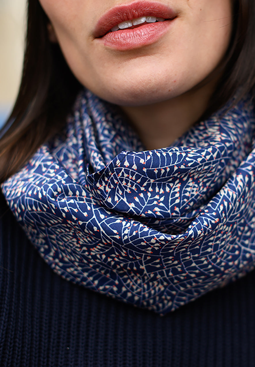 Foulard en soie 123 Meilleur Ami Paris, porté femme. Imprimé délicat de motifs blancs et roses et sur un fond bleu nuit.