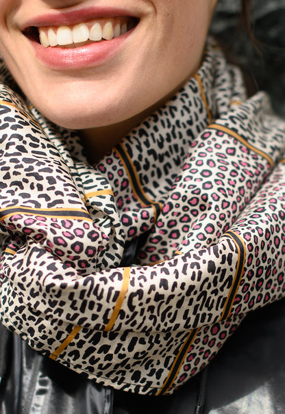 Foulard en soie 124 Meilleur Ami Paris, porté femme. Motifs léopard roses et noirs sur fond blanc avec rayures noires et or. 