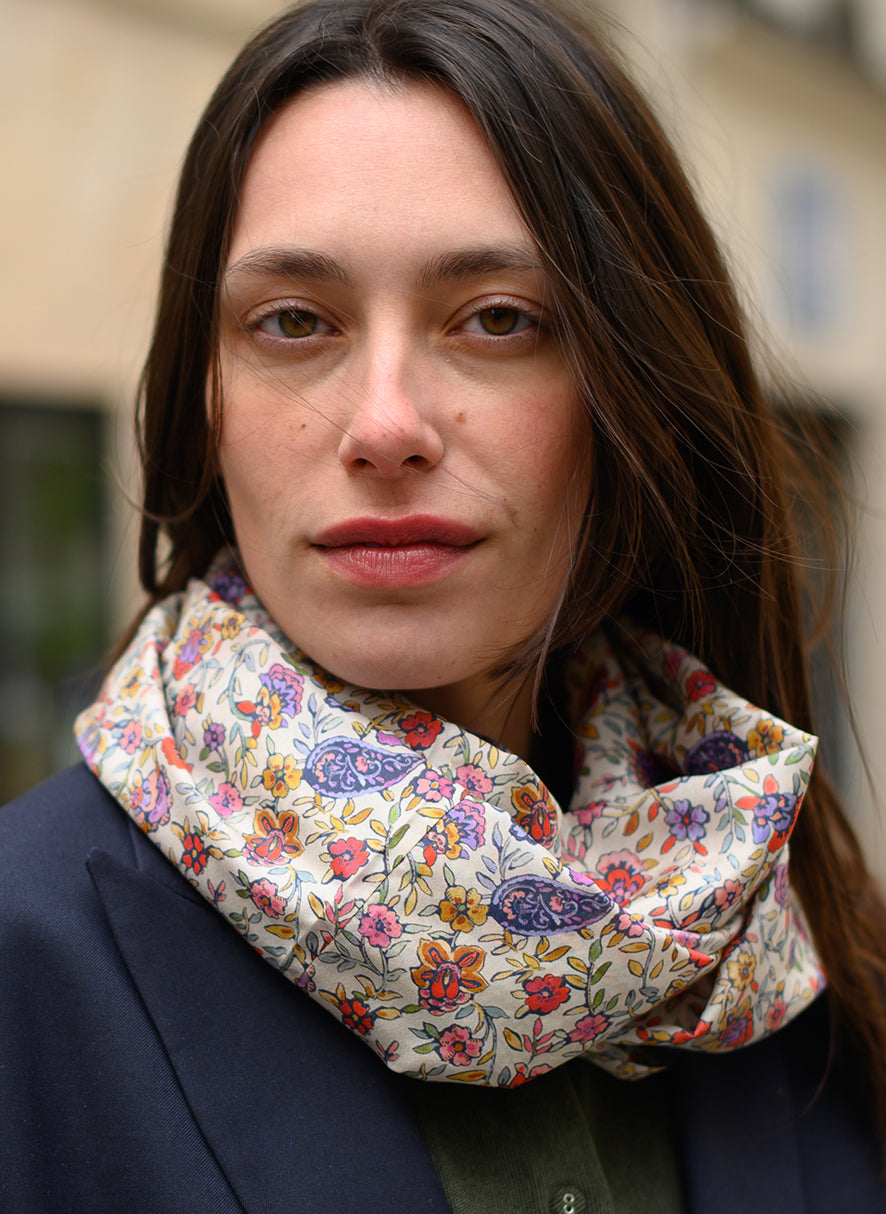 Foulard en soie Meilleur Ami Paris, porté femme sur veste bleu marine. Des fleurs colorées sur fond blanc, dans l'esprit d'un jardin anglais.