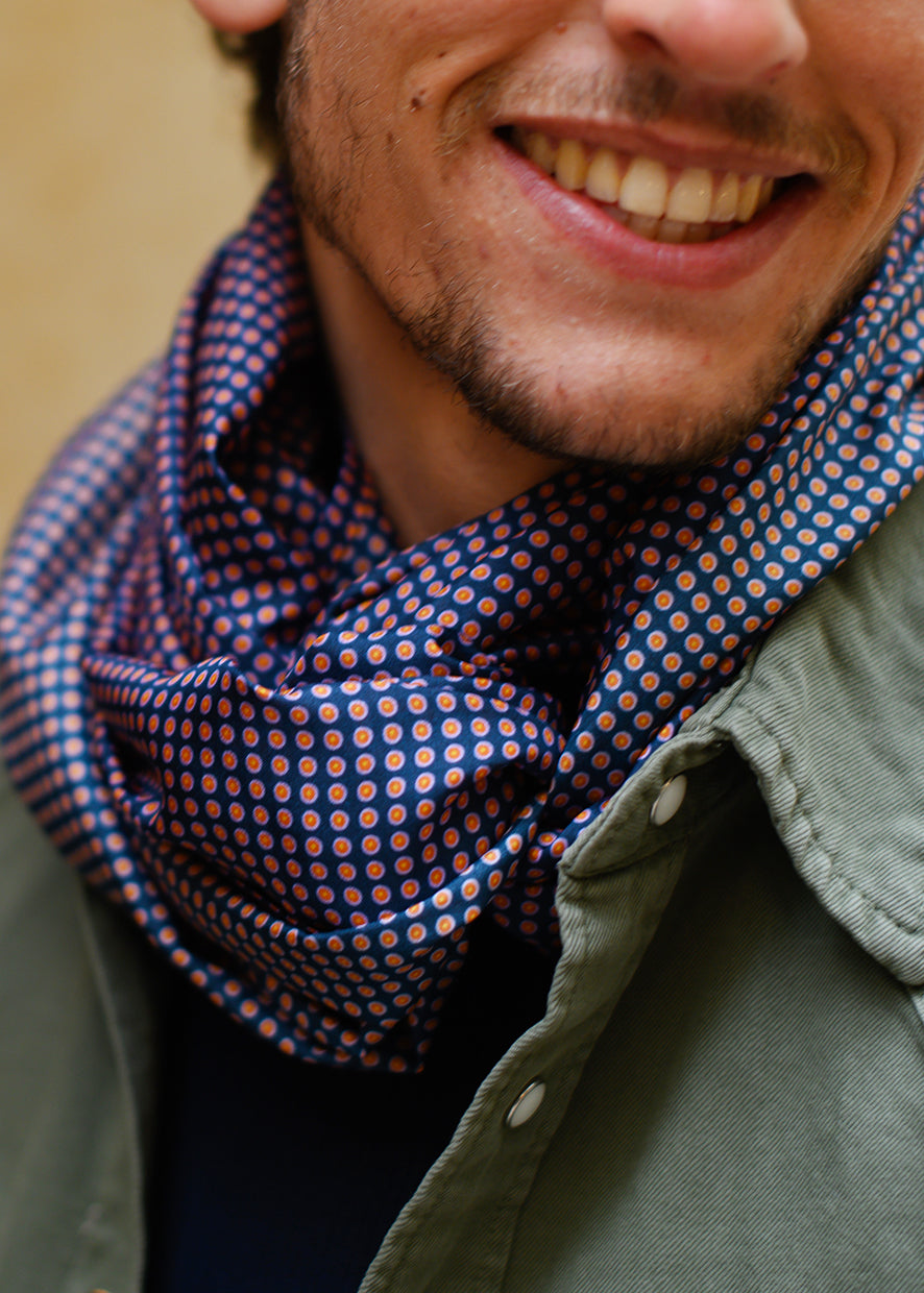 Foulard en soie 39 Meilleur Ami Paris, porté homme. Motifs à pois rouge orangé sur fond bleu nuit. 