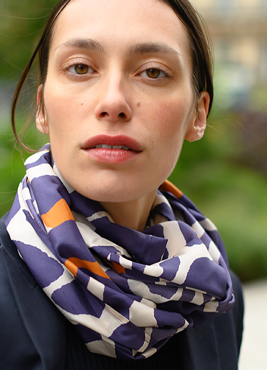 Foulard en soie 75 Meilleur Ami Paris, porté femme. Motifs oranges et bleu indigo sur fond blanc.