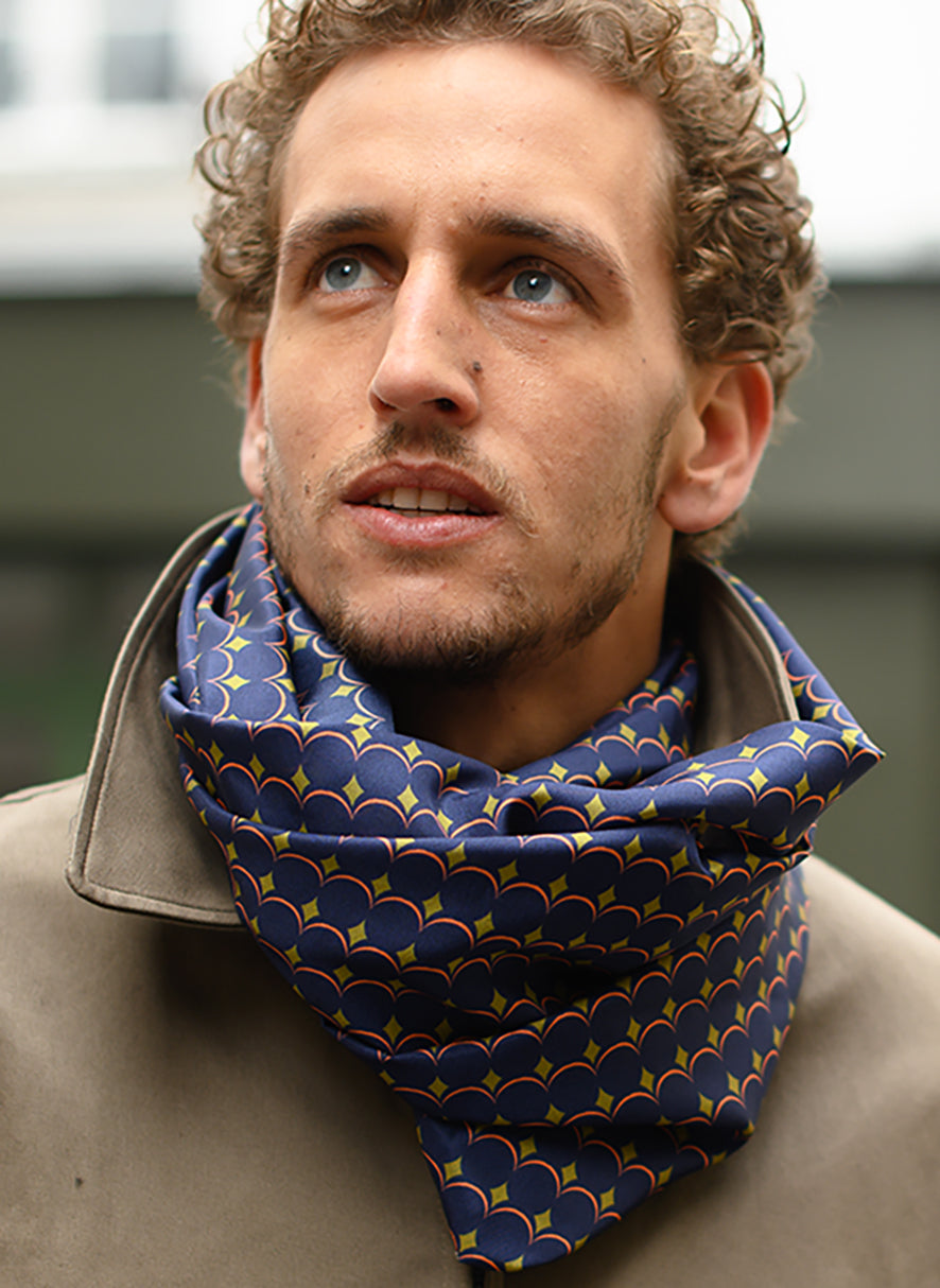 Foulard en soie 80 Meilleur Ami, porté homme. Inspiré de l'art cinétique, entre couleurs pop et bleu nuit.