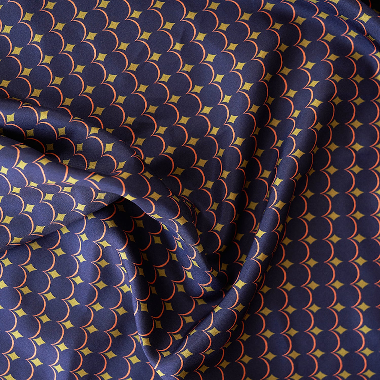 Foulard en soie 80 Meilleur Ami Paris. Gros plan sur les motifs bleu nuit, or et rouge orangé.