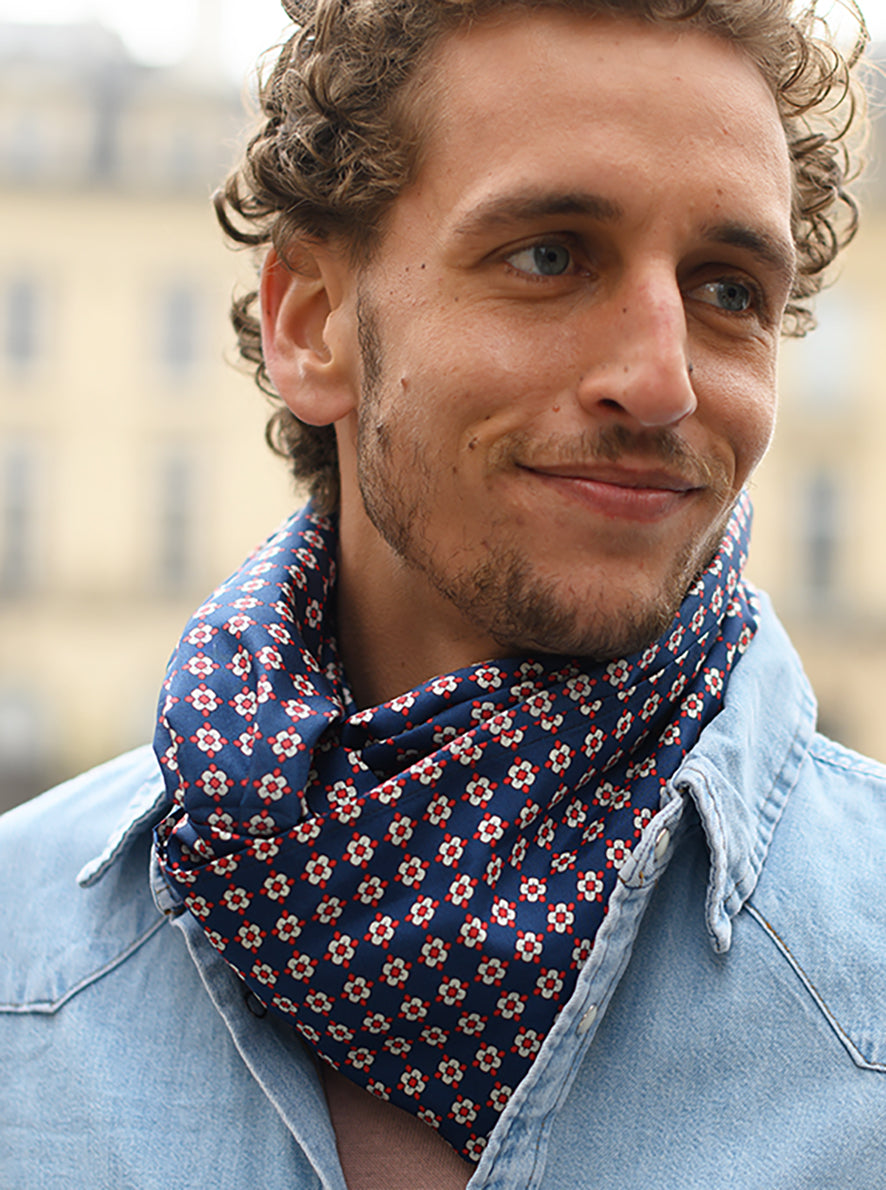 Foulard Soie 10, porté homme, Meilleur Ami Paris. Inspiré des motifs de cravates des années 60, petites fleurs rouges et blanches sur fond bleu marine.