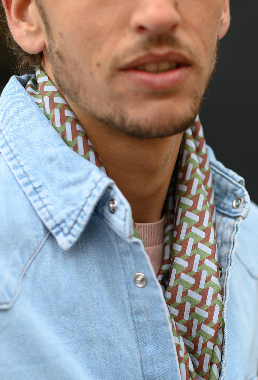 Foulard en soie 85 Meilleur Ami Paris, porté homme dénoué. Pas si classique, cet imprimé graphique vert et brun, un petit effet 3D.